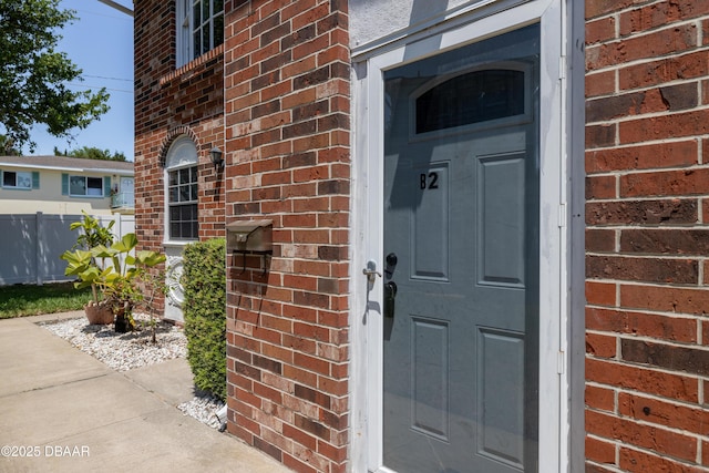 property entrance with fence and brick siding