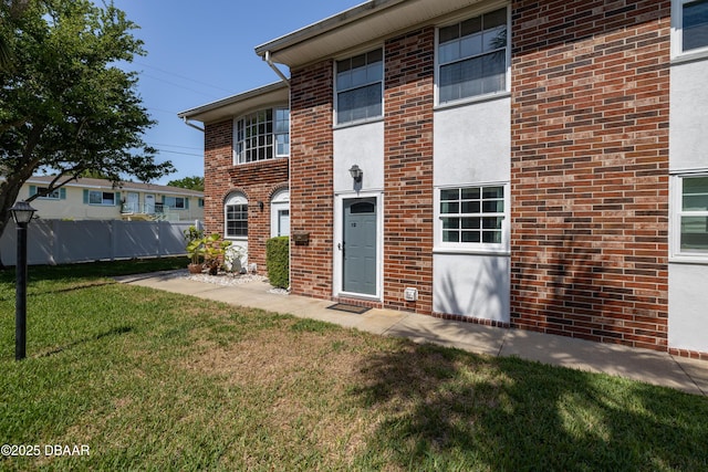 view of front of house with fence, a front lawn, and brick siding