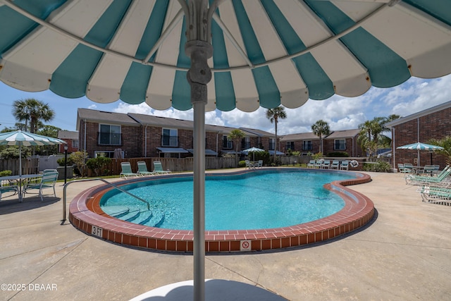 pool with a patio, a residential view, and fence