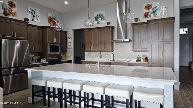 kitchen featuring appliances with stainless steel finishes, sink, hanging light fixtures, a kitchen island with sink, and dark brown cabinetry