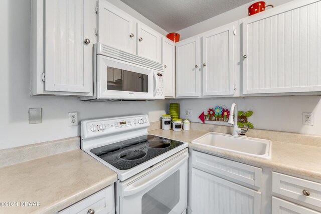 kitchen featuring white cabinets, a textured ceiling, sink, and white appliances