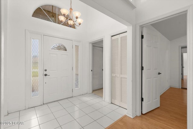 tiled entryway with a notable chandelier