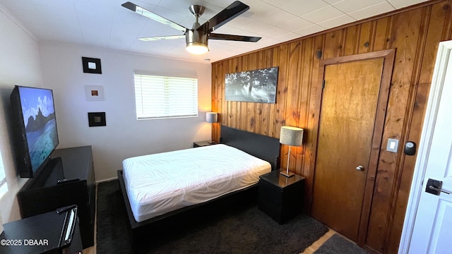 bedroom featuring wooden walls and ceiling fan