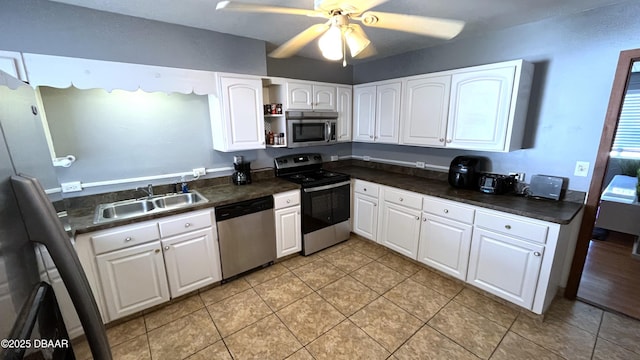 kitchen featuring dark countertops, a sink, white cabinets, stainless steel appliances, and open shelves