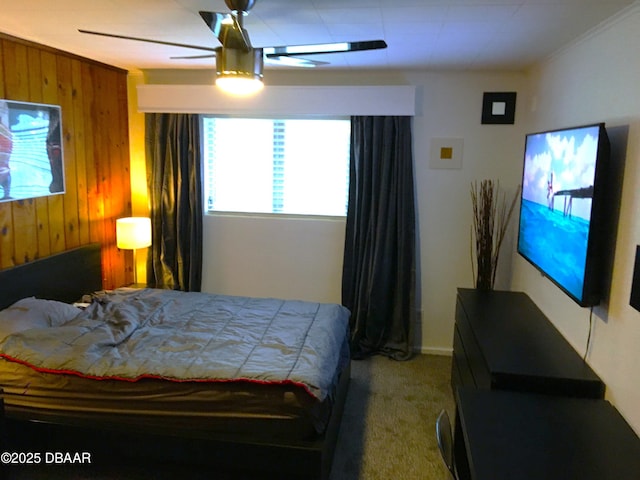 carpeted bedroom featuring wooden walls and a ceiling fan