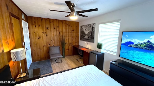 bedroom featuring wood walls, ceiling fan, and wood finished floors