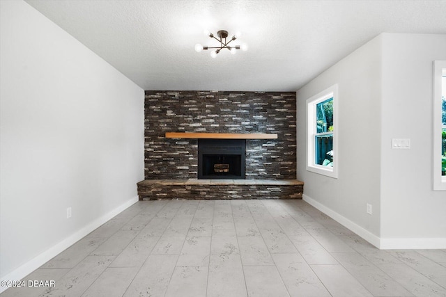 unfurnished living room with a fireplace, a chandelier, a textured ceiling, and light wood-type flooring