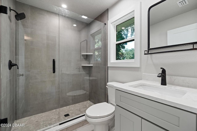 bathroom with toilet, vanity, an enclosed shower, and a textured ceiling