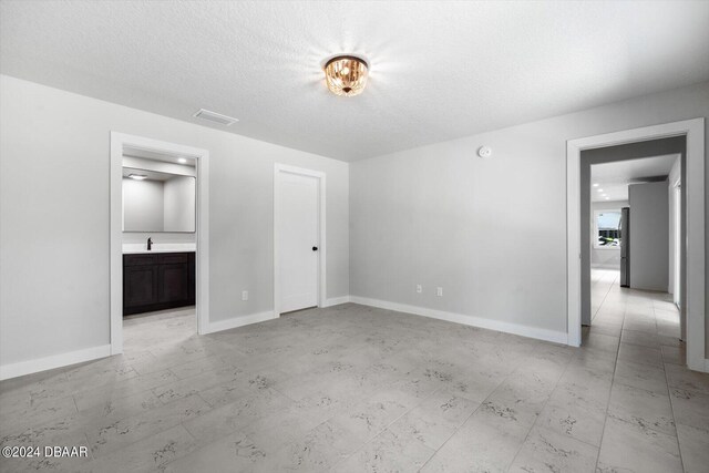 interior space with connected bathroom, sink, and a textured ceiling