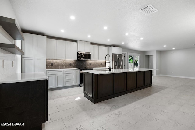 kitchen featuring backsplash, a center island with sink, white cabinetry, and appliances with stainless steel finishes