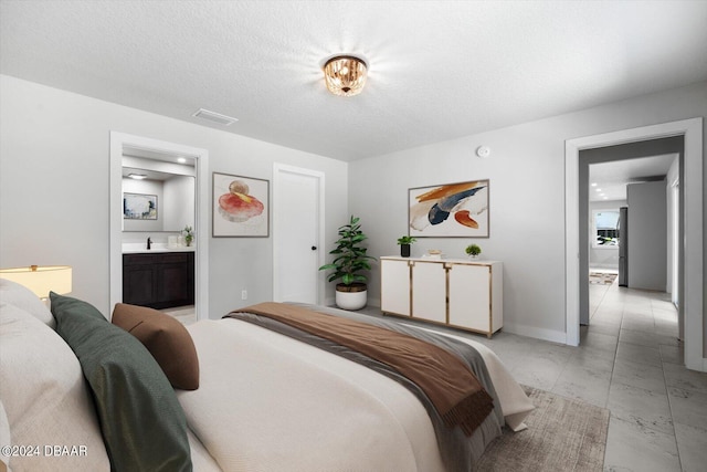 bedroom with connected bathroom, sink, and a textured ceiling