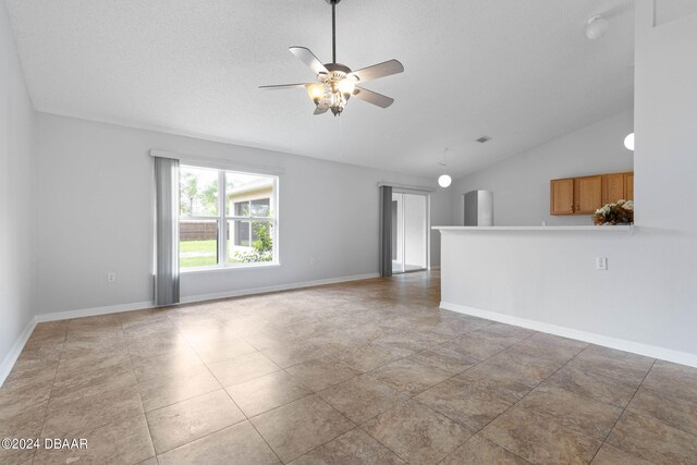 unfurnished living room with a textured ceiling, tile patterned flooring, lofted ceiling, and ceiling fan