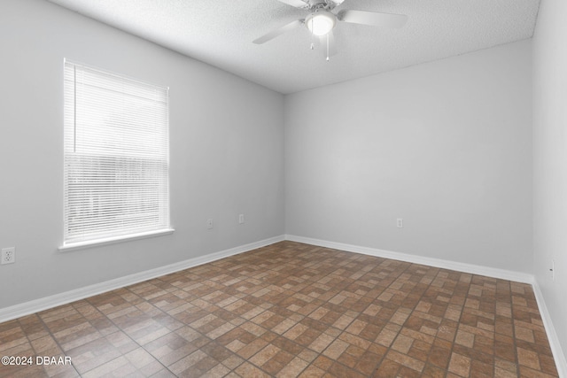 empty room with ceiling fan, plenty of natural light, and a textured ceiling