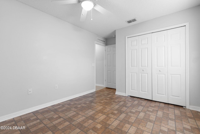 unfurnished bedroom featuring ceiling fan, a textured ceiling, and a closet