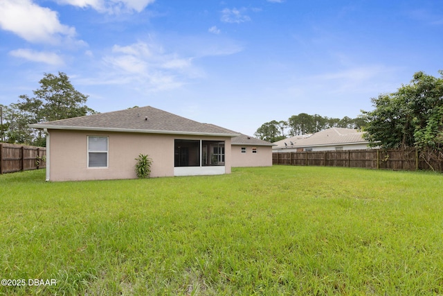 rear view of property featuring a fenced backyard, a yard, and stucco siding