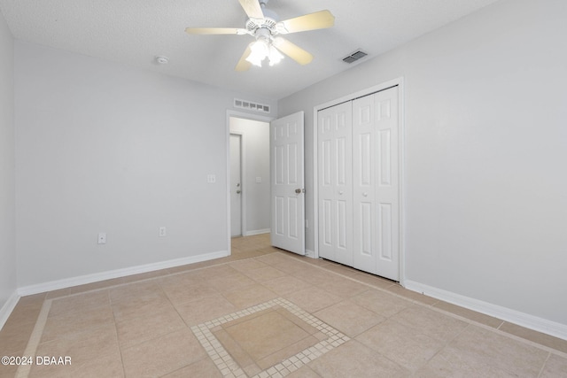 unfurnished bedroom with a textured ceiling, light tile patterned floors, ceiling fan, and a closet