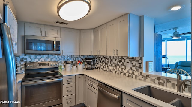 kitchen with ceiling fan, sink, decorative backsplash, and appliances with stainless steel finishes