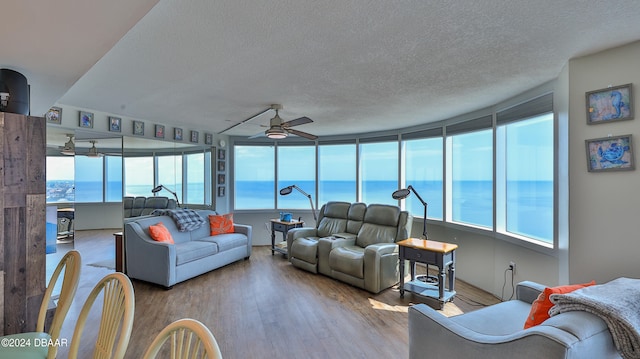 living room with a water view, ceiling fan, a healthy amount of sunlight, and light wood-type flooring