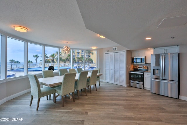 dining area featuring a textured ceiling, light wood-type flooring, and a notable chandelier