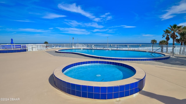 view of swimming pool with a patio area, a water view, and a community hot tub