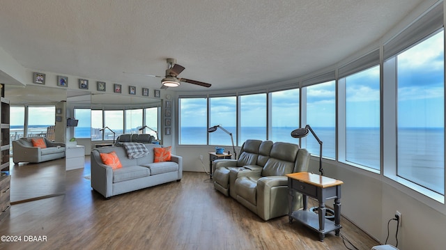 sunroom featuring ceiling fan and a water view