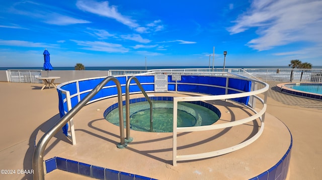 view of swimming pool featuring a community hot tub and a water view