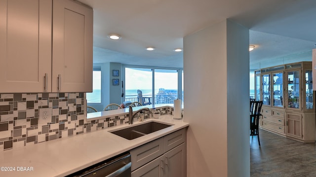 kitchen with tasteful backsplash, white cabinetry, sink, dishwasher, and a water view