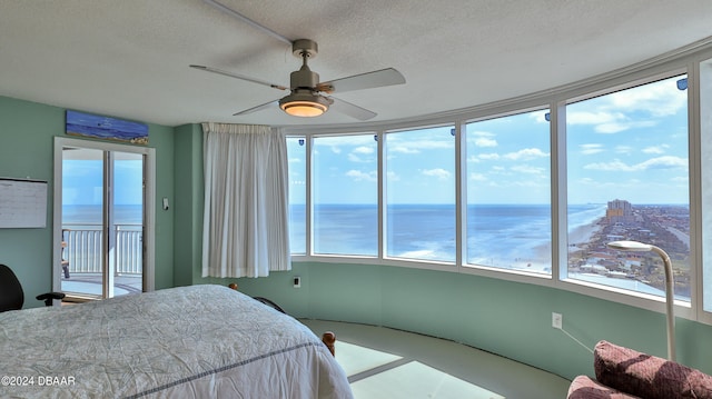 bedroom featuring a textured ceiling, access to exterior, a water view, and ceiling fan