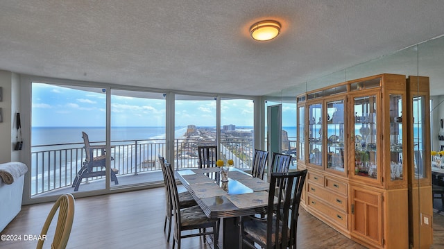 dining area featuring dark wood-type flooring, plenty of natural light, a water view, and floor to ceiling windows