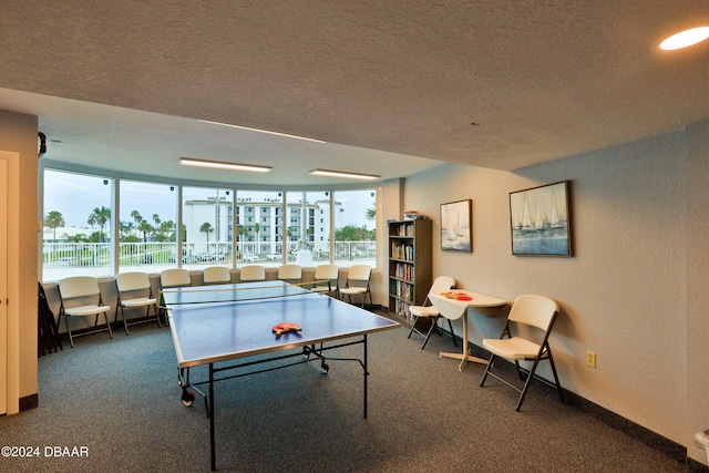 game room with a textured ceiling and dark colored carpet