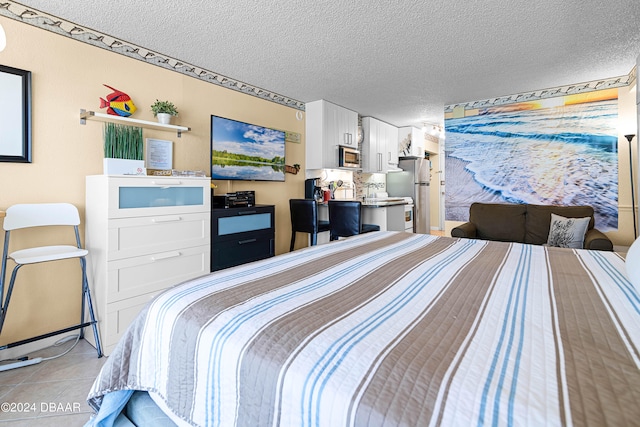 bedroom featuring stainless steel refrigerator, a textured ceiling, and light tile patterned floors