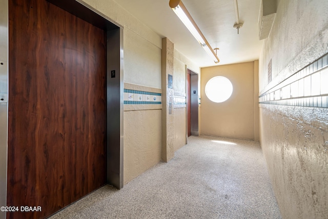 corridor featuring elevator and light carpet