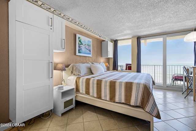 bedroom with light tile patterned flooring, multiple windows, and a water view