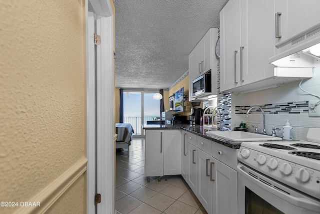 kitchen featuring tasteful backsplash, sink, white electric range, and white cabinets