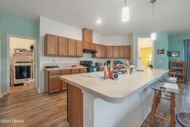 kitchen with washer / dryer, dark hardwood / wood-style floors, hanging light fixtures, a kitchen breakfast bar, and black range with electric stovetop