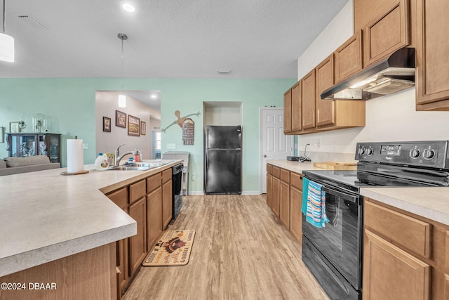 kitchen with black appliances, a textured ceiling, sink, light hardwood / wood-style flooring, and decorative light fixtures