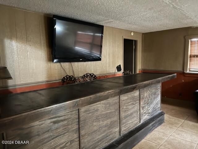 bar featuring a textured ceiling and light tile patterned flooring