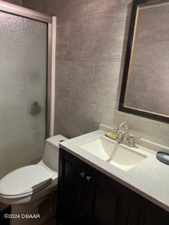 bathroom with toilet, vanity, and a shower with door