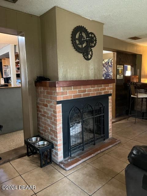 living room with a fireplace, a textured ceiling, and tile patterned floors