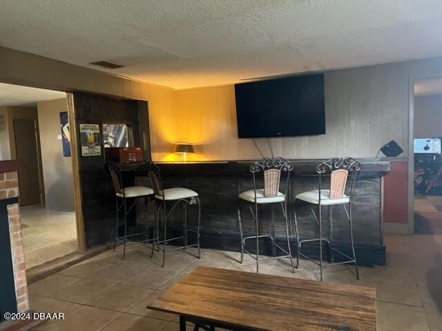 bar with a textured ceiling and tile patterned floors