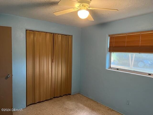 unfurnished bedroom with a textured ceiling, light carpet, ceiling fan, and a closet