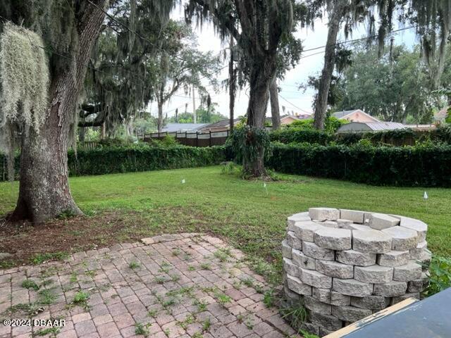 view of yard featuring an outdoor fire pit and a patio