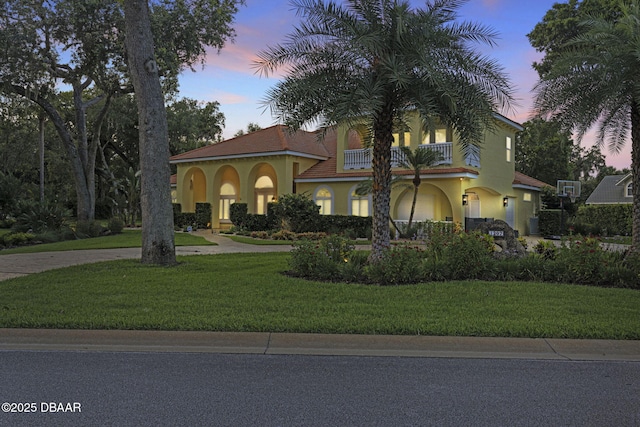 1207 Kaleen Dr, Ormond Beach, FL 32174 - mediterranean / spanish house featuring a balcony, stucco siding, curved driveway, and a yard