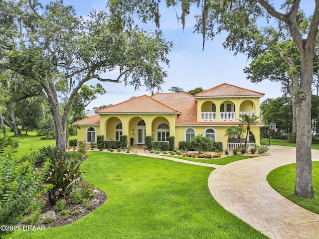 1207 Kaleen Dr, Ormond Beach, FL 32174 - mediterranean / spanish-style home featuring curved driveway, a balcony, stucco siding, and a front yard