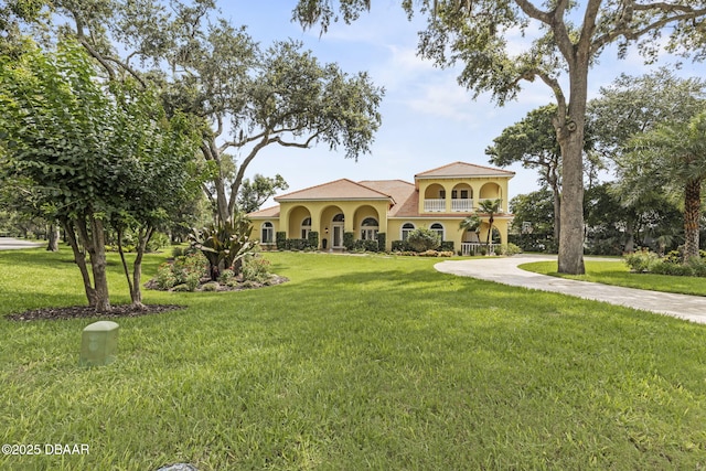 1207 Kaleen Dr, Ormond Beach, FL 32174 - mediterranean / spanish-style house with stucco siding, a front lawn, a balcony, and driveway