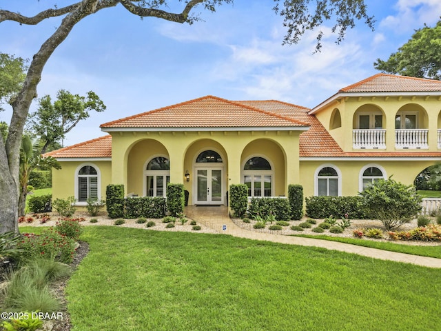 1207 Kaleen Dr, Ormond Beach, FL 32174 - mediterranean / spanish-style home featuring french doors, stucco siding, a front lawn, a tile roof, and a balcony
