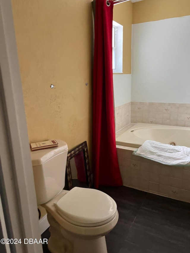 bathroom with toilet and tiled tub