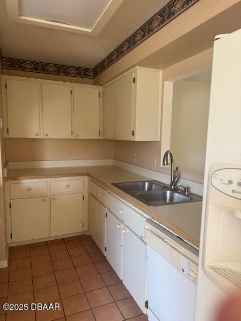 kitchen with white cabinetry, white appliances, light tile patterned flooring, and sink