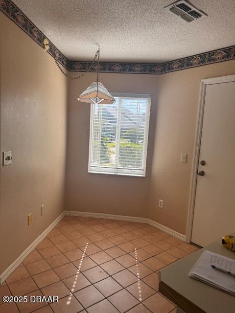 unfurnished dining area featuring tile patterned flooring and a textured ceiling