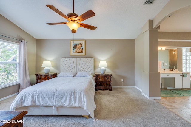 bedroom featuring light carpet, ceiling fan, and ensuite bathroom